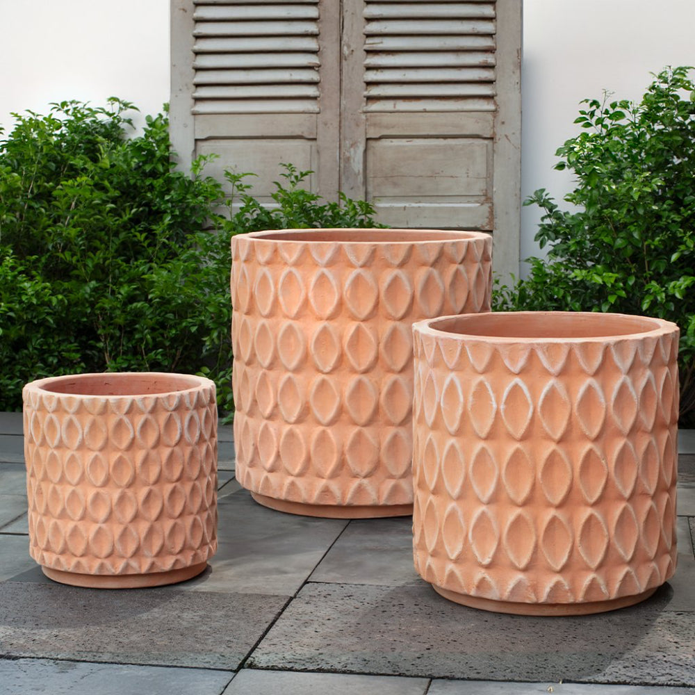 Three terracotta-colored planters with textured patterns on a patio.