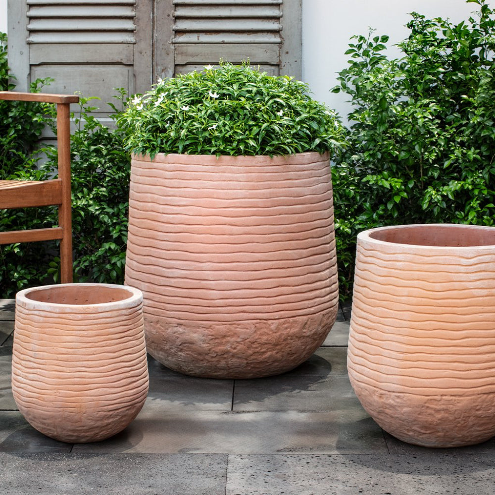 Three terracotta planters with wavy texture on a patio