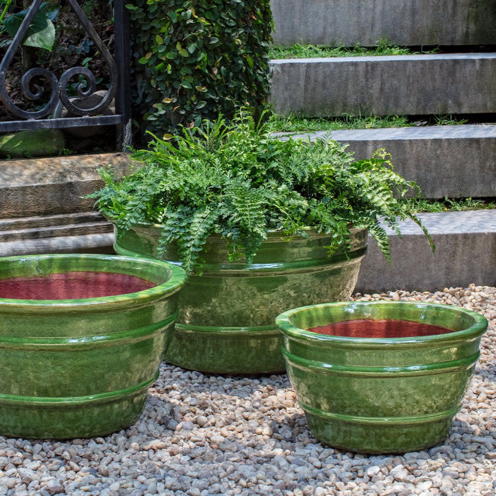 Green ceramic planters with plants on a pebble ground and stone steps background