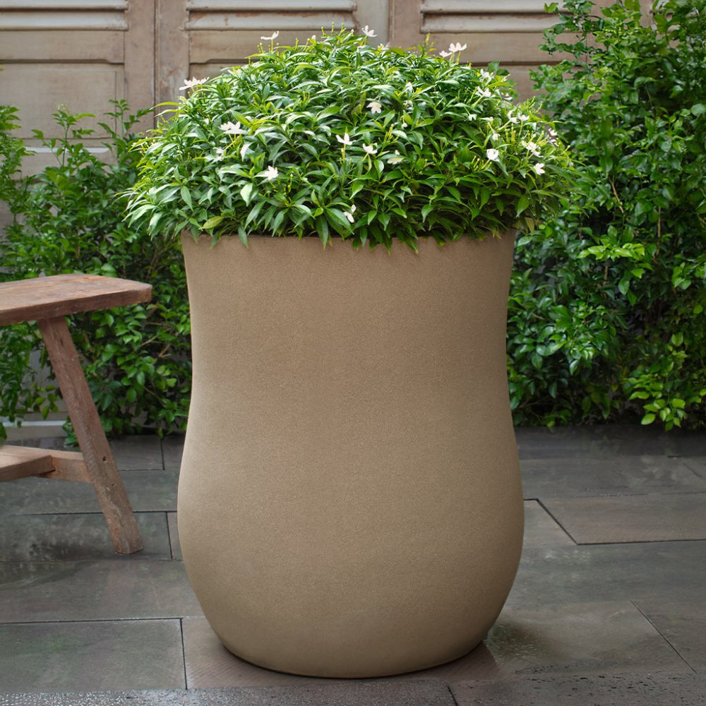 Beige planter with green foliage and white flowers on a patio
