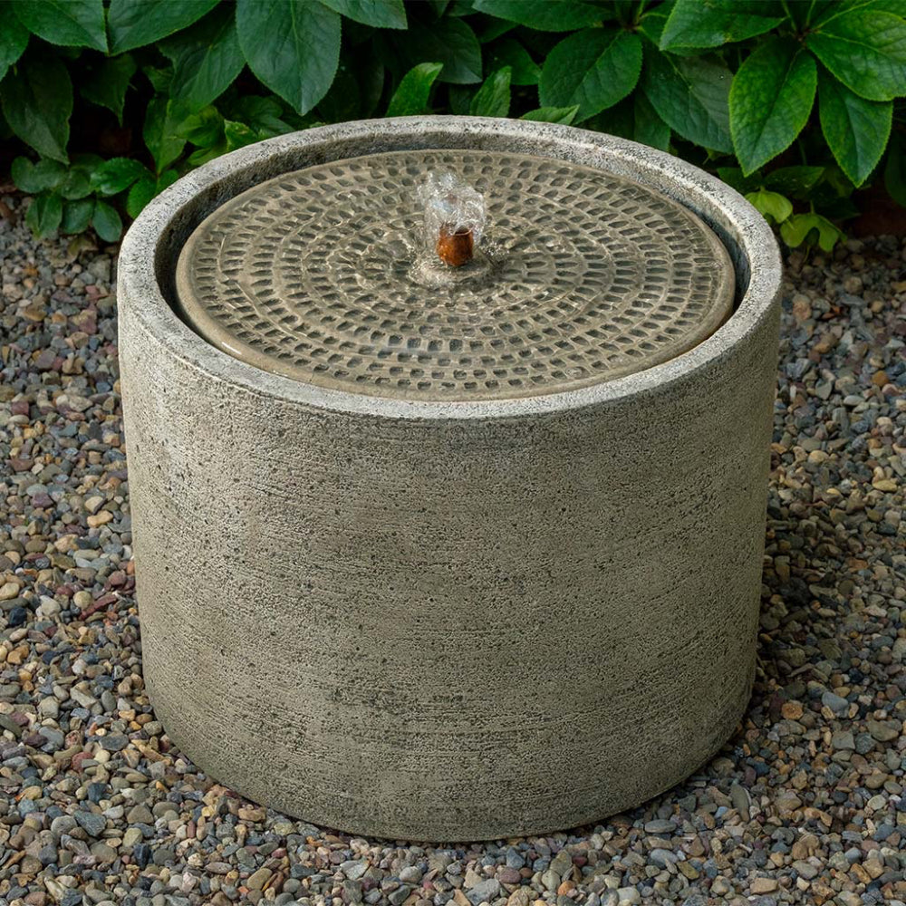 Cast stone outdoor fountain with decorative water feature on a gravel surface