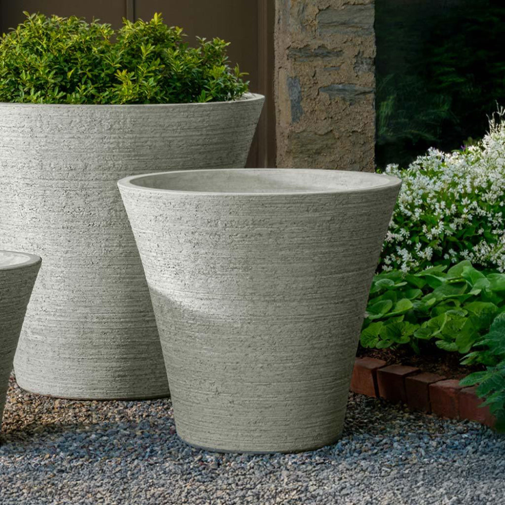 Gray stone planters with greenery in a garden setting