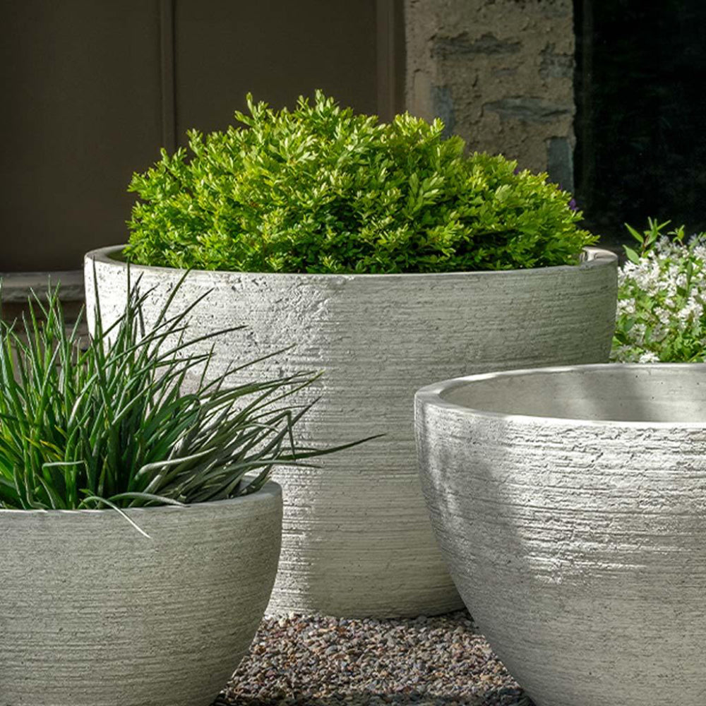 Decorative stone planters with green plants against a neutral background