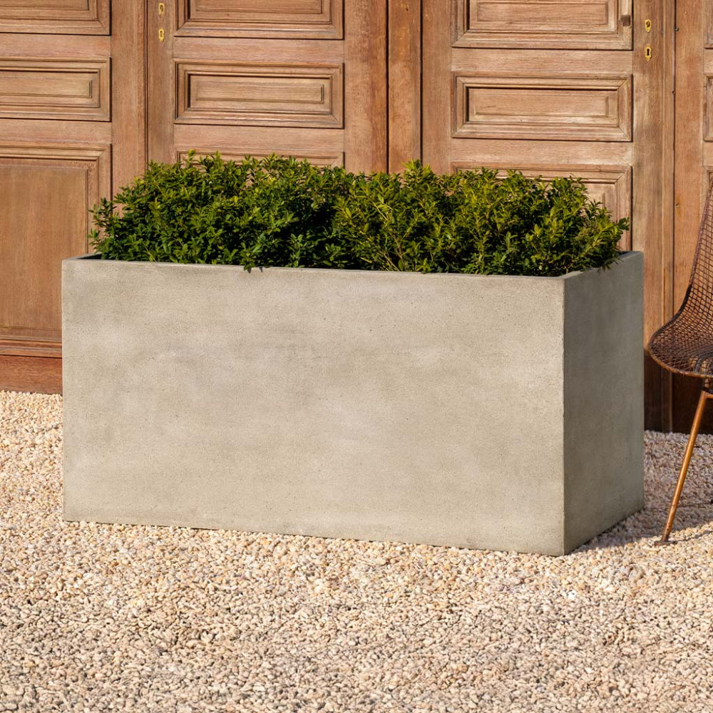 Rectangular concrete planter with green plants against a wooden background