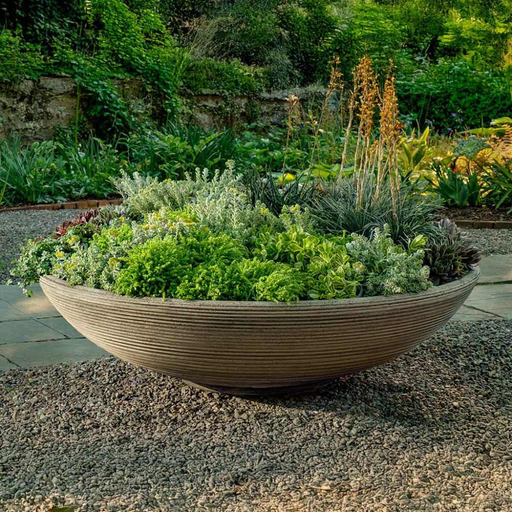 Decorative garden bowl planter with greenery in a garden setting